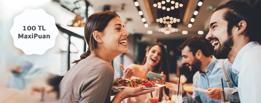 restoran da oturan 2 kişi yemek yiyor, 100 tl maxipuan ibaresi