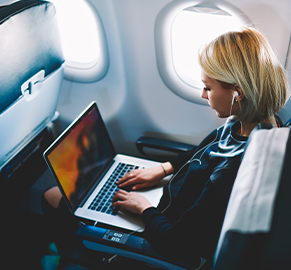 Uçakta dizüstü bilgisayarıyla çalışan bir kadın görseli